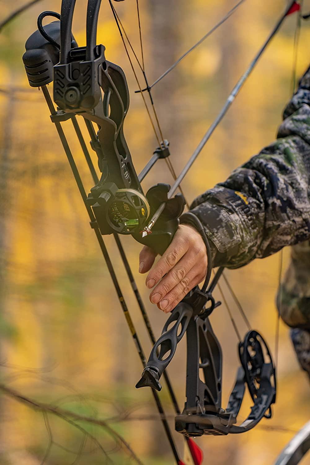 Close-up of a compound bow with broadhead arrow, camo jacket, outdoor hunting setting