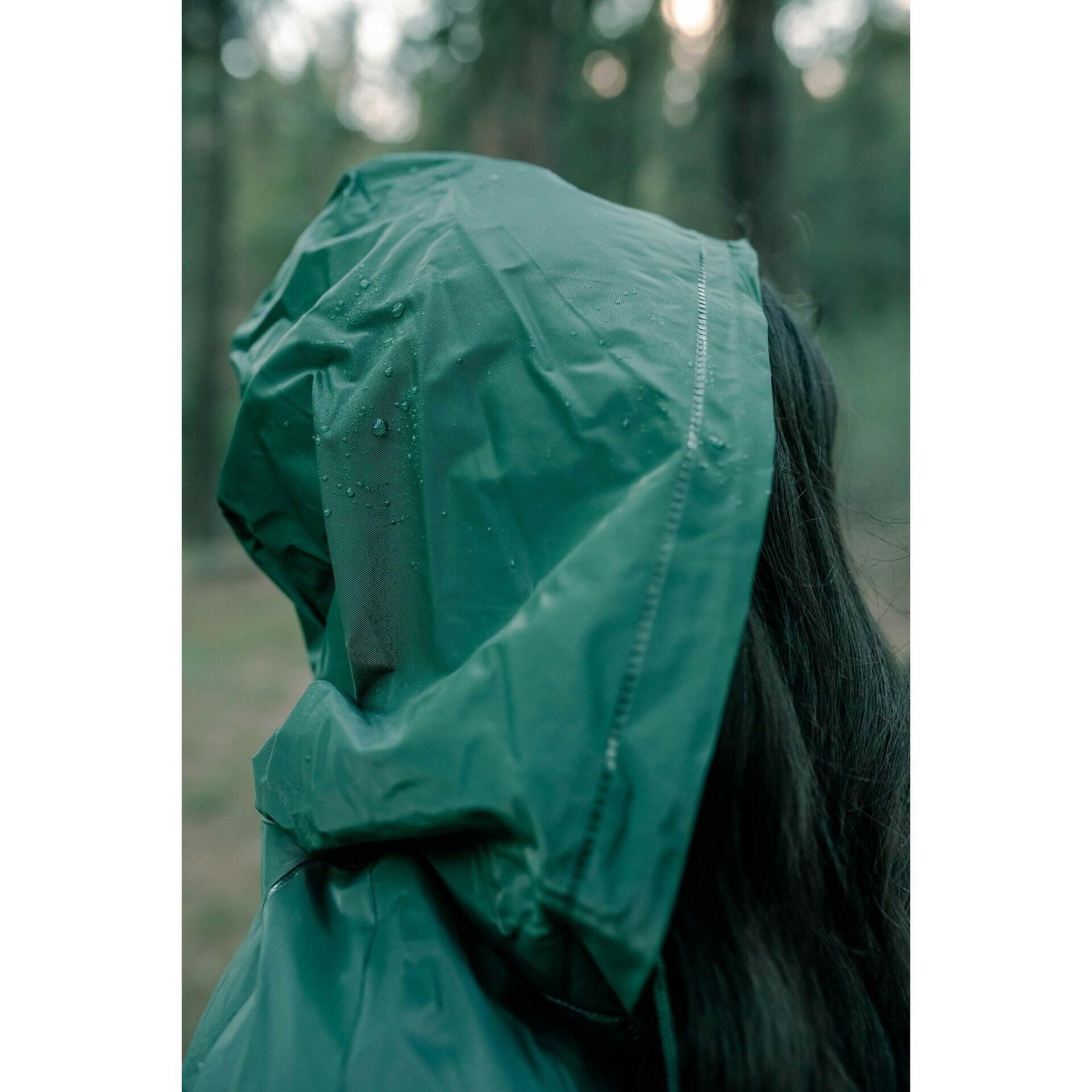 Person wearing green waterproof rain suit with hood outdoors in forest