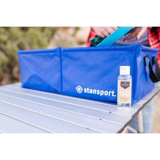 Stansport all-purpose camper’s soap bottle on camp table with blue Stansport tote