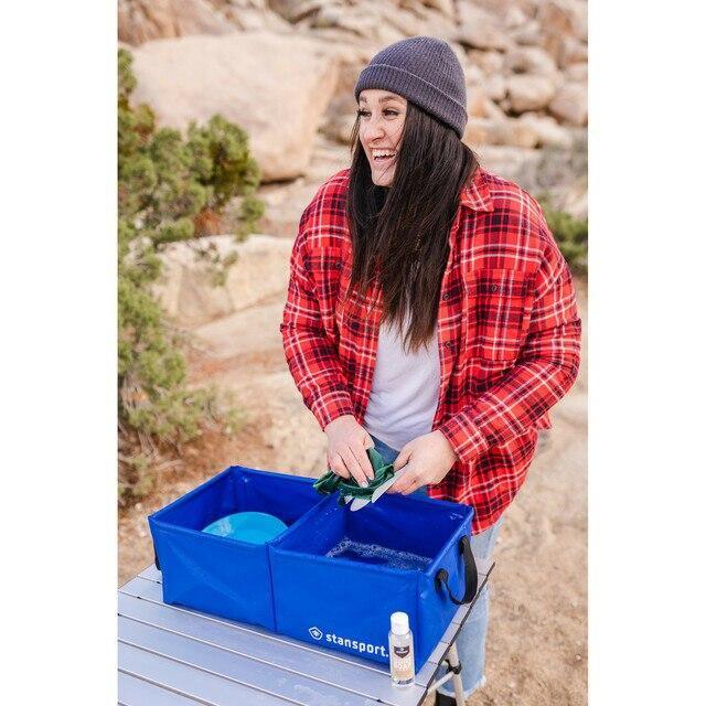 Woman washing dishes outdoors with Stansport camper soap and blue wash bins