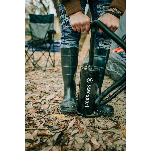Stansport double action hand pump used outdoors on leafy ground at a campsite