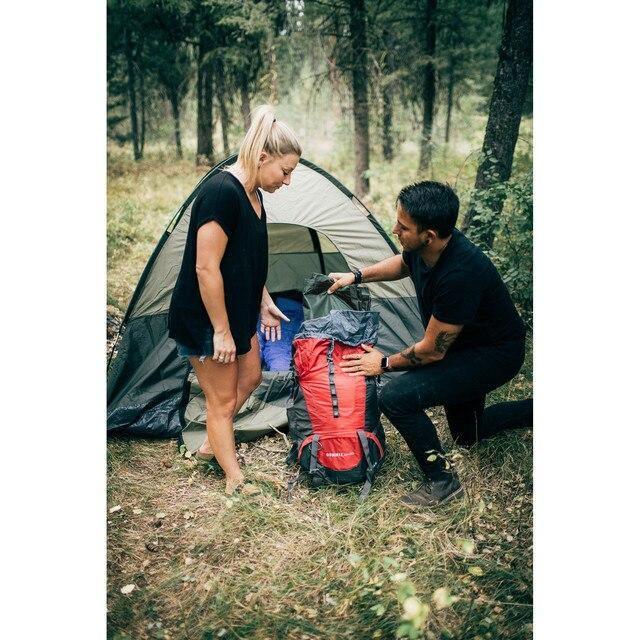 Two people camping with a tent and red hiking backpack in a forest setting