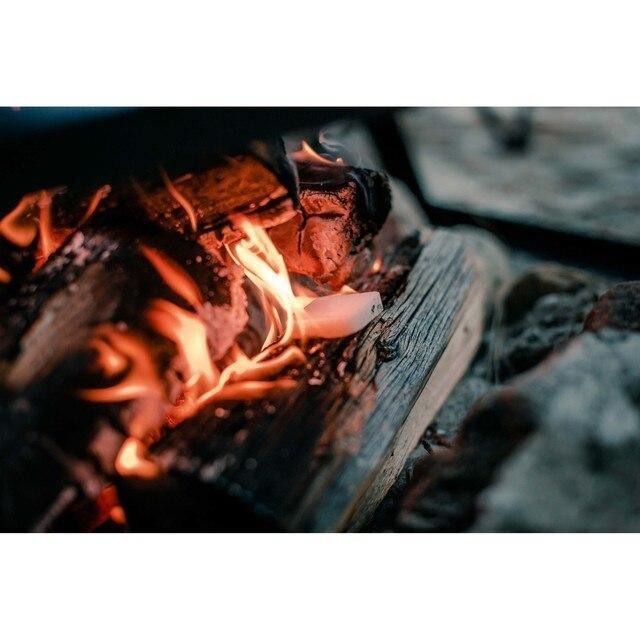 Solid fuel tablet burning on campfire wood outdoors, campfire starter close-up.