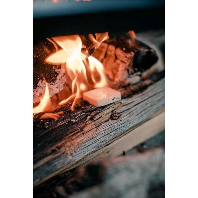 Solid fuel tablet burning on campfire wood, outdoor fire starter for camping