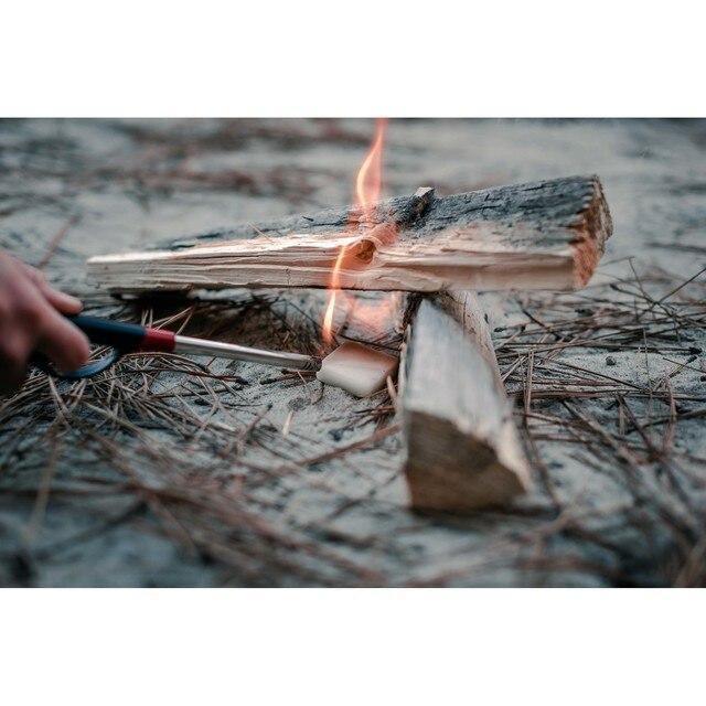Hand lighting firewood with solid fuel tablets outdoors, camping fire starter scene