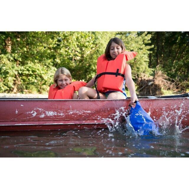 Children with orange life jackets in a red canoe, using a blue waterproof dry bag on water
