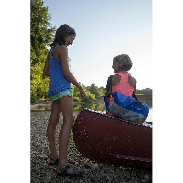 Two kids by a lake with a red canoe and a blue Stansport waterproof dry bag