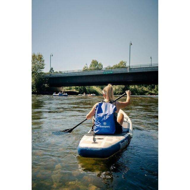 Woman paddle boarding on river with Stansport waterproof dry bag and bridge in background