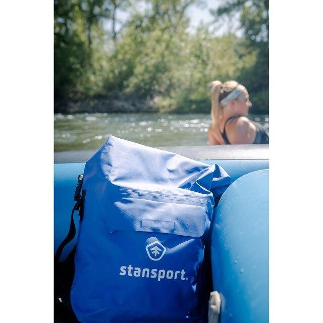 Stansport blue waterproof dry bag on inflatable raft by river with woman in background