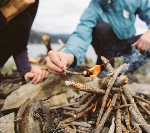 Person using Zippo Emergency Fire Kit to light campfire outdoors with kindling and rocks