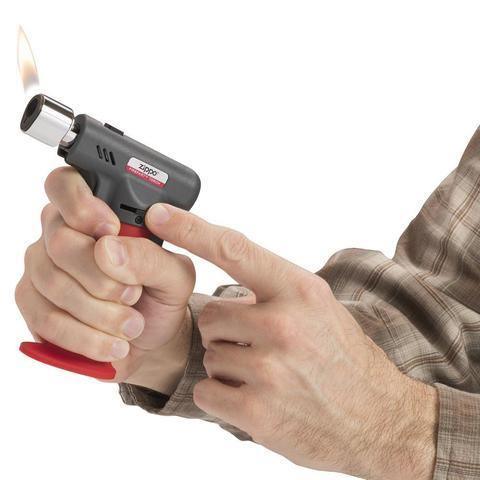 Person holding a Zippo FireFast torch lighter with visible flame against white background